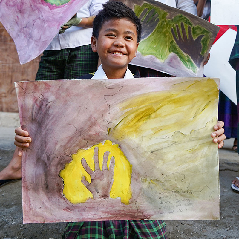 Ein Junge in Myanmar präsentiert sein Kunstwerk.